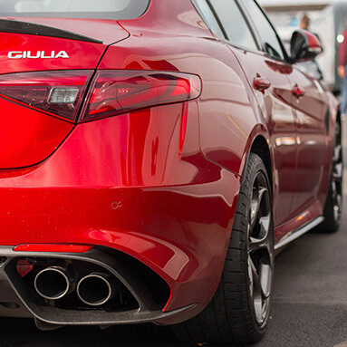 Close up rear shot of Alfa Romeo Giulia exhaust and tyres on side.