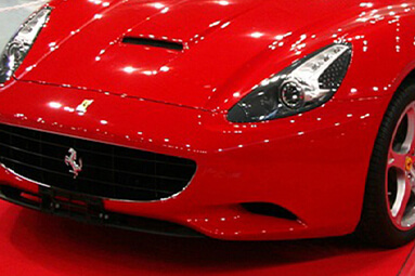 Red Ferrari California parked in car exhibition with crowd in background