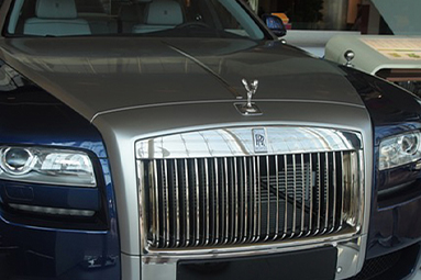 Blue and silver Rolls Royce Ghost, parked and on display on white platform