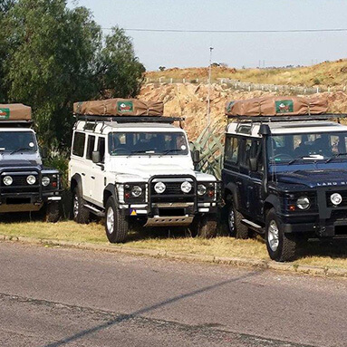 3 Land Rover Defender 4-wheel drive cars on the side of the road with dry, grassy, hilly background