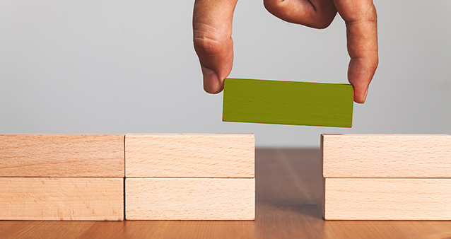 Hand bridging gap with green block, symbolizing comparing medical aid to find best fit