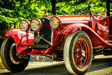 Classic red Alfa Romeo on dirt road, close front view shot.