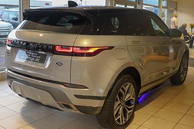 Black side view of a grey ranger rover velar.