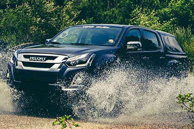 Black Isuzu double cab splashing through shallow water 