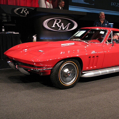 Red Chevrolet Stingray in an auction showroom.