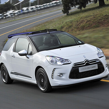 White Citroën DS3 cabriolets on the road with a tree in the background.