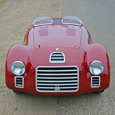Rear-view image of classic red ferrari parked on side of road.