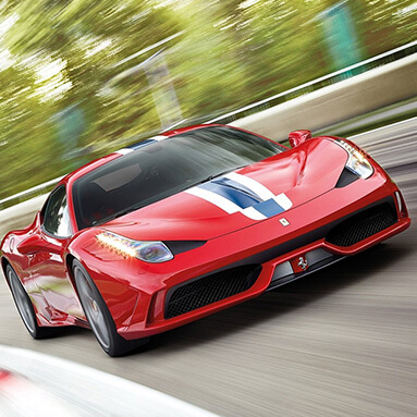 Red ferrari v8 with blue and white strips riving on track at high speed with slight blurring from movement.
