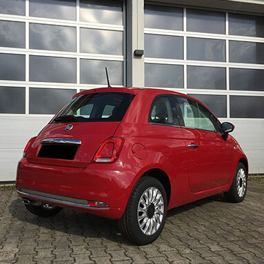 Red Fiat 500 facing a  white door of a closed garage