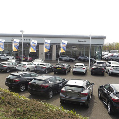 Cars parked in front of an Infiniti dealership.