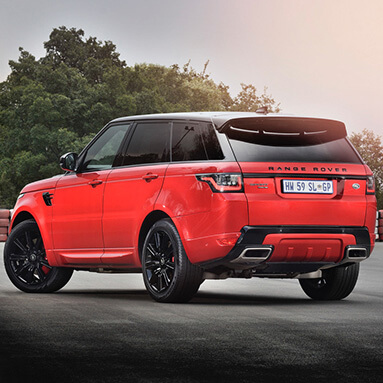 Back view of a red and black Range Rover parked on an empty road