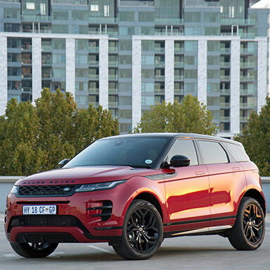 Side view of a red Range Rover with high-rise building in the background