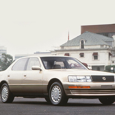 Lexus IS 400 on the road with white building in the background.