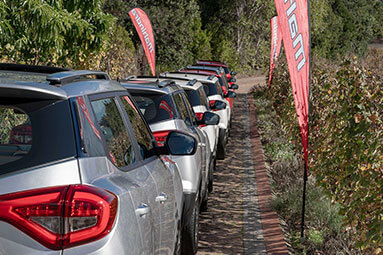 Silver and white Mahindra XUV300 vehicles in a que at a car show.