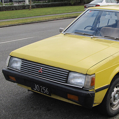 Front side view of a yellow 1980 Mitsubishi Lancer.