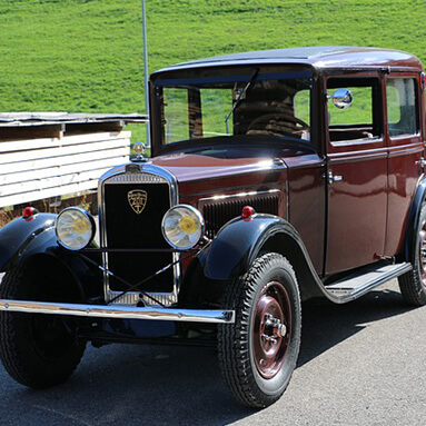 Brown, classic peugeot old timer parked sideways on tar with grass in background