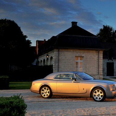 Rolls-Royce on wet road with snow-capped mountains in the background