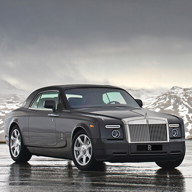 Rolls-Royce Phantom coupe parked in front of luxurious courtyard.