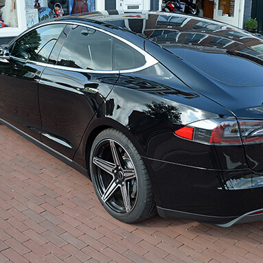 Back side view of a black Tesla Model S.
