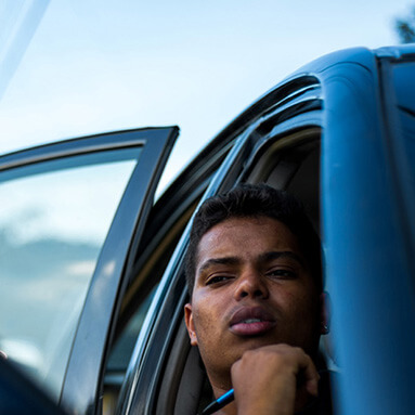 Man sitting in a car holding a pen and thinking.