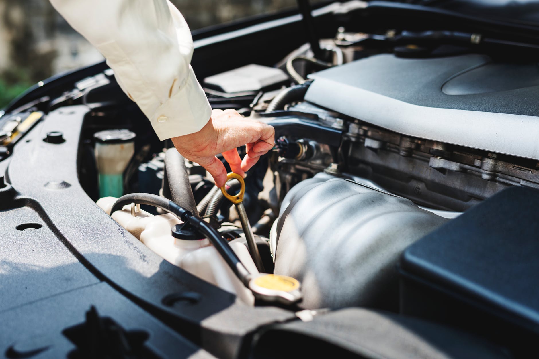 Man checking the oil with car hood open