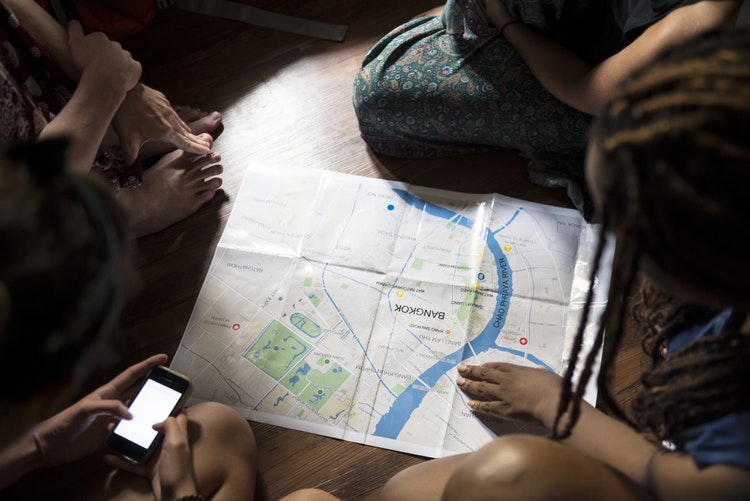 Group of friends planning trip with map on the floor.