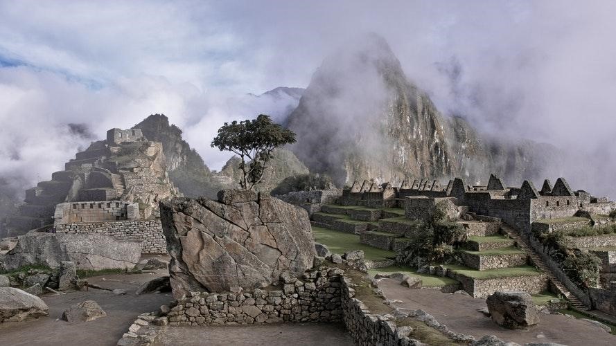 Burial site ruins with trees and clouds on mountain