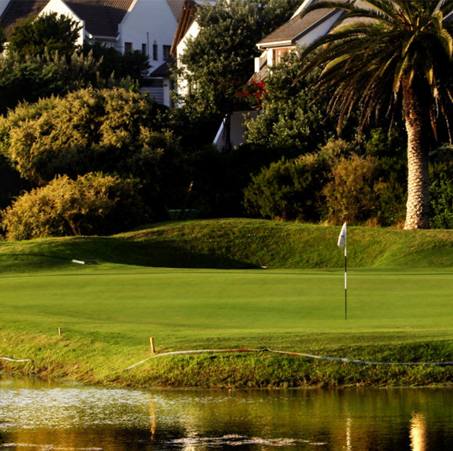 St Francis Links golf course buildings hidden amongst trees in background with golf course in the middle and a body of water in front.