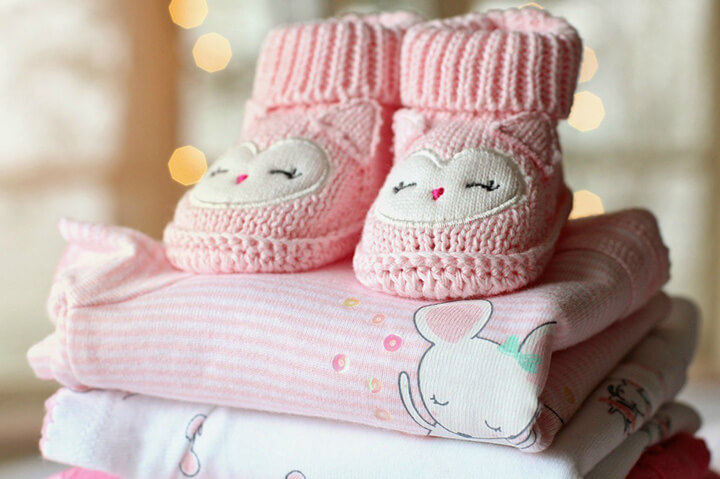 Pink knitted baby booties and baby clothes
