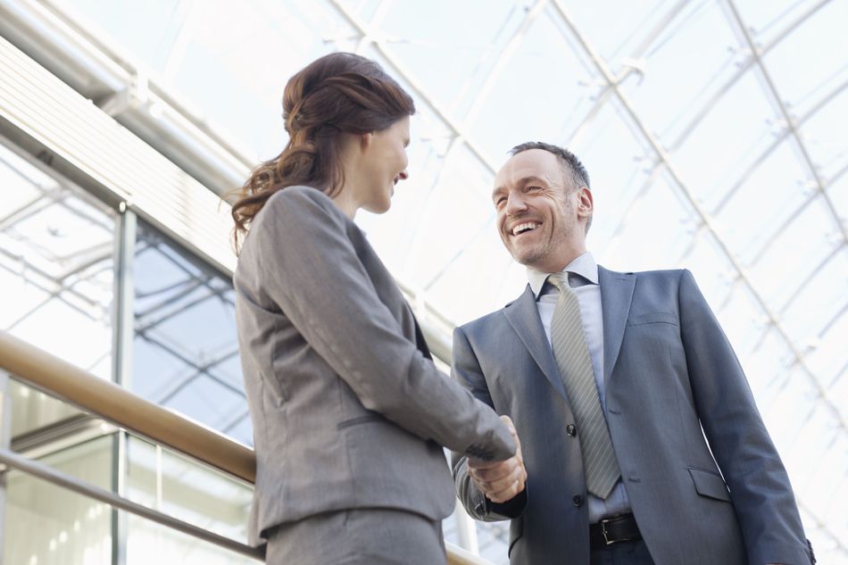 Woman and man shaking hands and smiling.