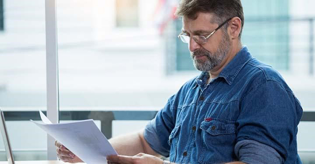 Man wearing glasses reading a paper.