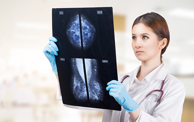 Female gynecologist looking at a mammogram checking for breast cancer at a hospital.