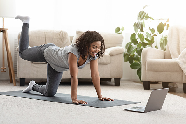 Women stretching in front of laptop while re-evaluating her finances under lockdown