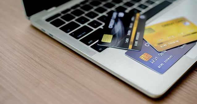 Credit cards on laptop illustrating different approaches to managing your debt