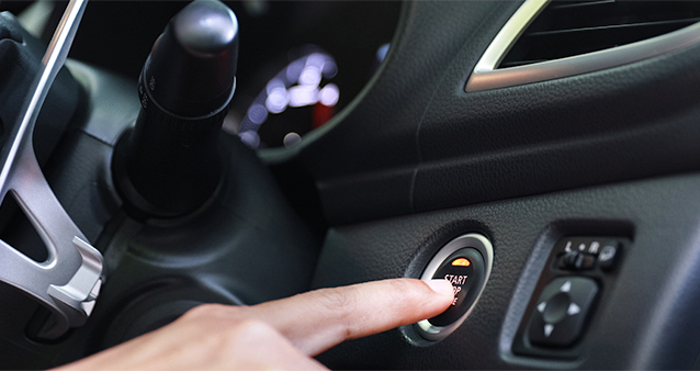 Finger pushing a start button inside a car
