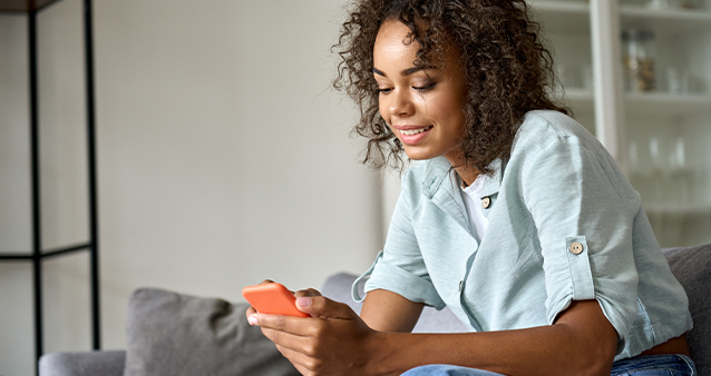 Smiling woman sitting on a couch with a cellphone in hand