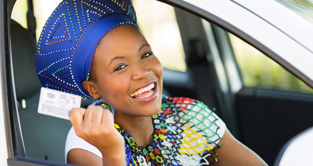 a woman holds up her new driver's licence she obtained in 2021 by following our guide