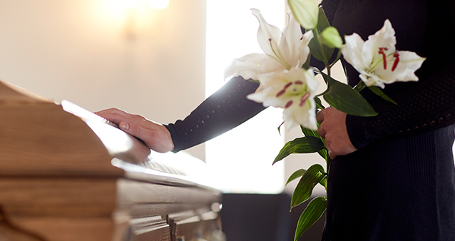 Woman with coffin at funeral paid for by funeral cover