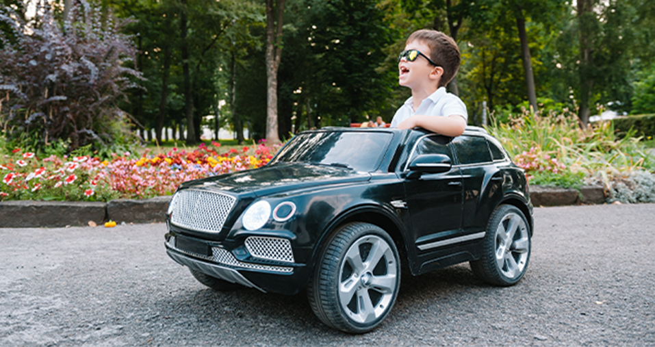 A young boy sitting in a toy Bentley