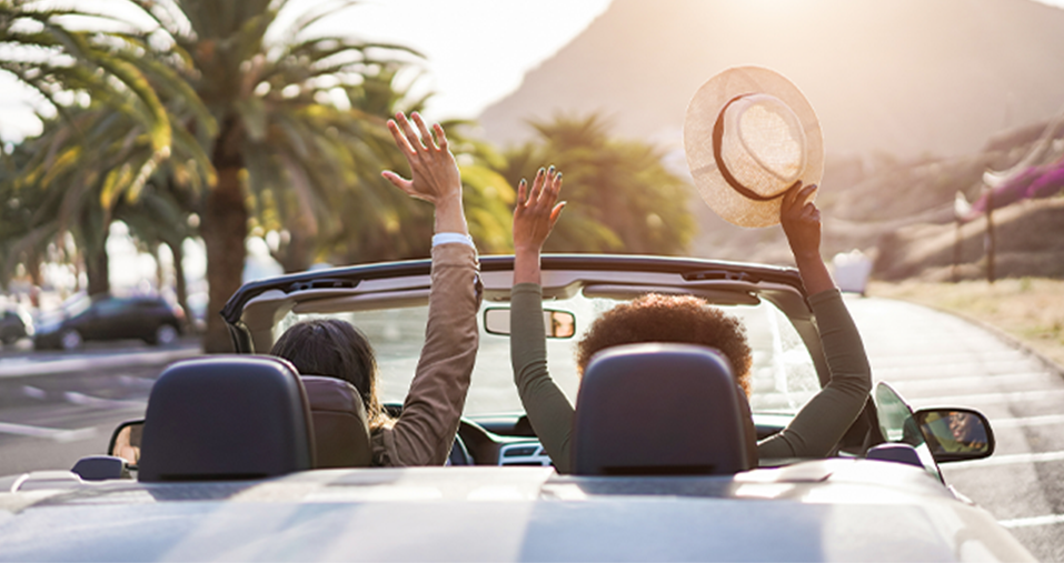 A couple with raised hands in a convertible car