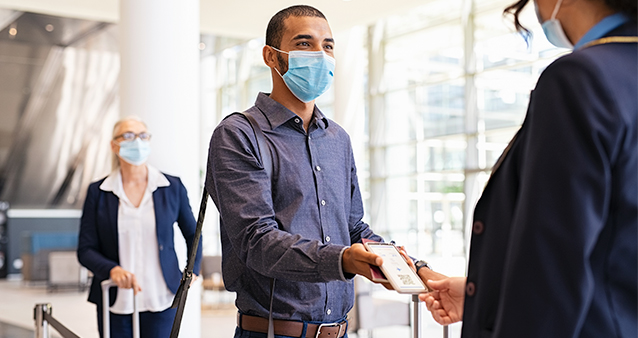 A man wearing a mask showing a digital boarding pass at an airport