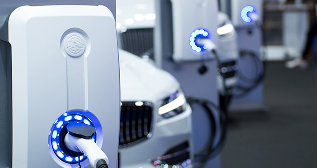 a row of electric vehicles parked at a charging station