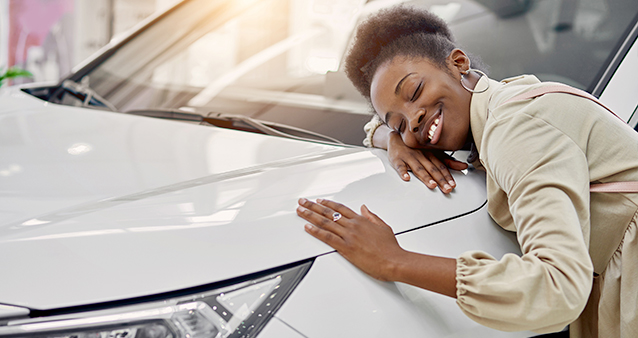 a smiling woman hugging a white car