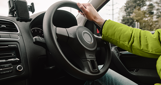 man with one hand on steering wheel