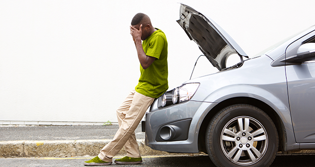 Man with head in hands by broken down car