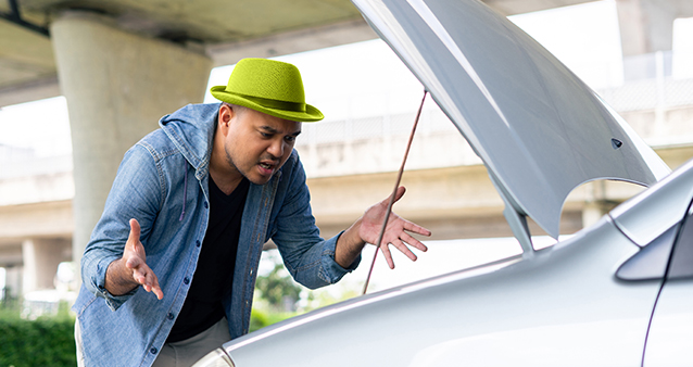 man looking into open car engine