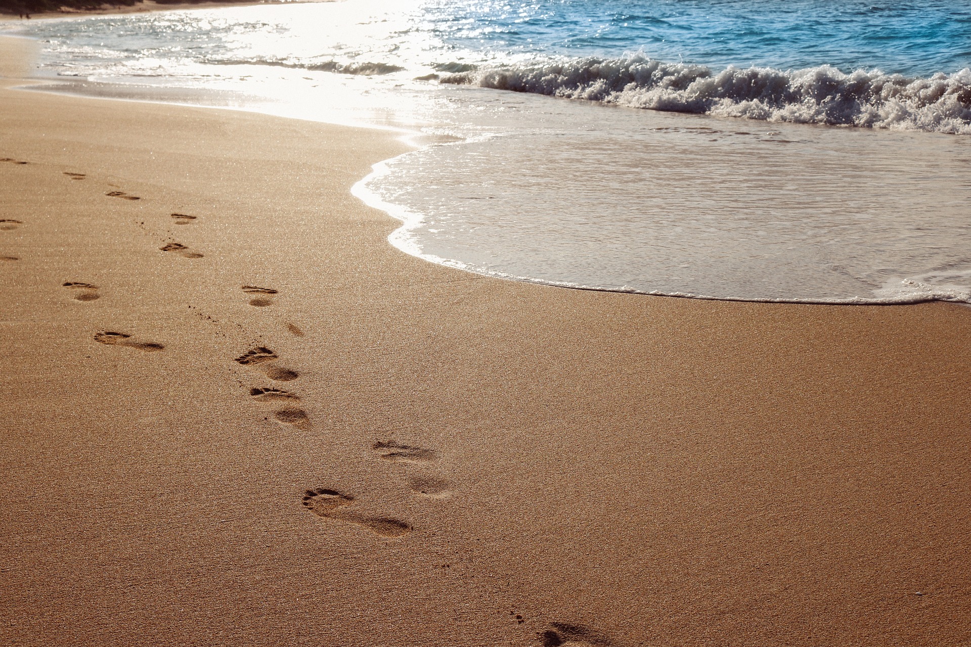 Footprints on wet sandy beach.