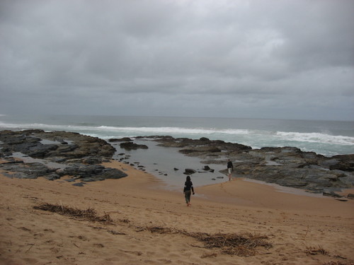 Two people strolling on a rocky beach 