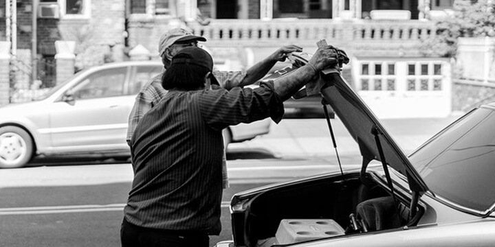 Two men at the open hood/bonnet of a car chatting. 