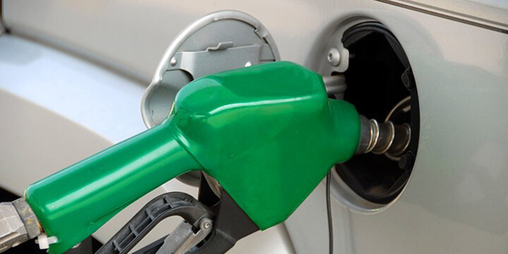 Green petrol pump refuelling a silver car.